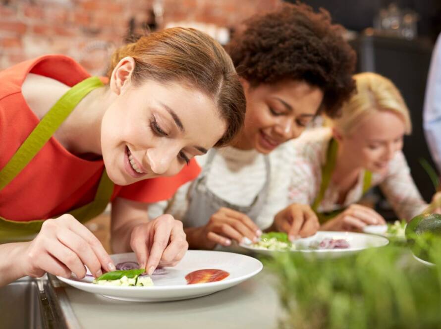 Agencia viajes a Vietnam: viajeros participando en una divertida clase de cocina tradicional como experiencia inmersiva.