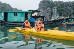 Pareja en kayak explorando una aldea flotante en la bahía de Ha Long, viaje a Vietnam y Camboya de 15 días