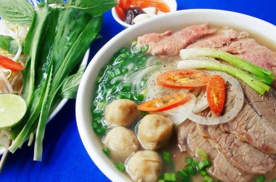 Mejor agencia para viajar a Vietnam: un auténtico tazón de sopa Pho tradicional con hierbas frescas.