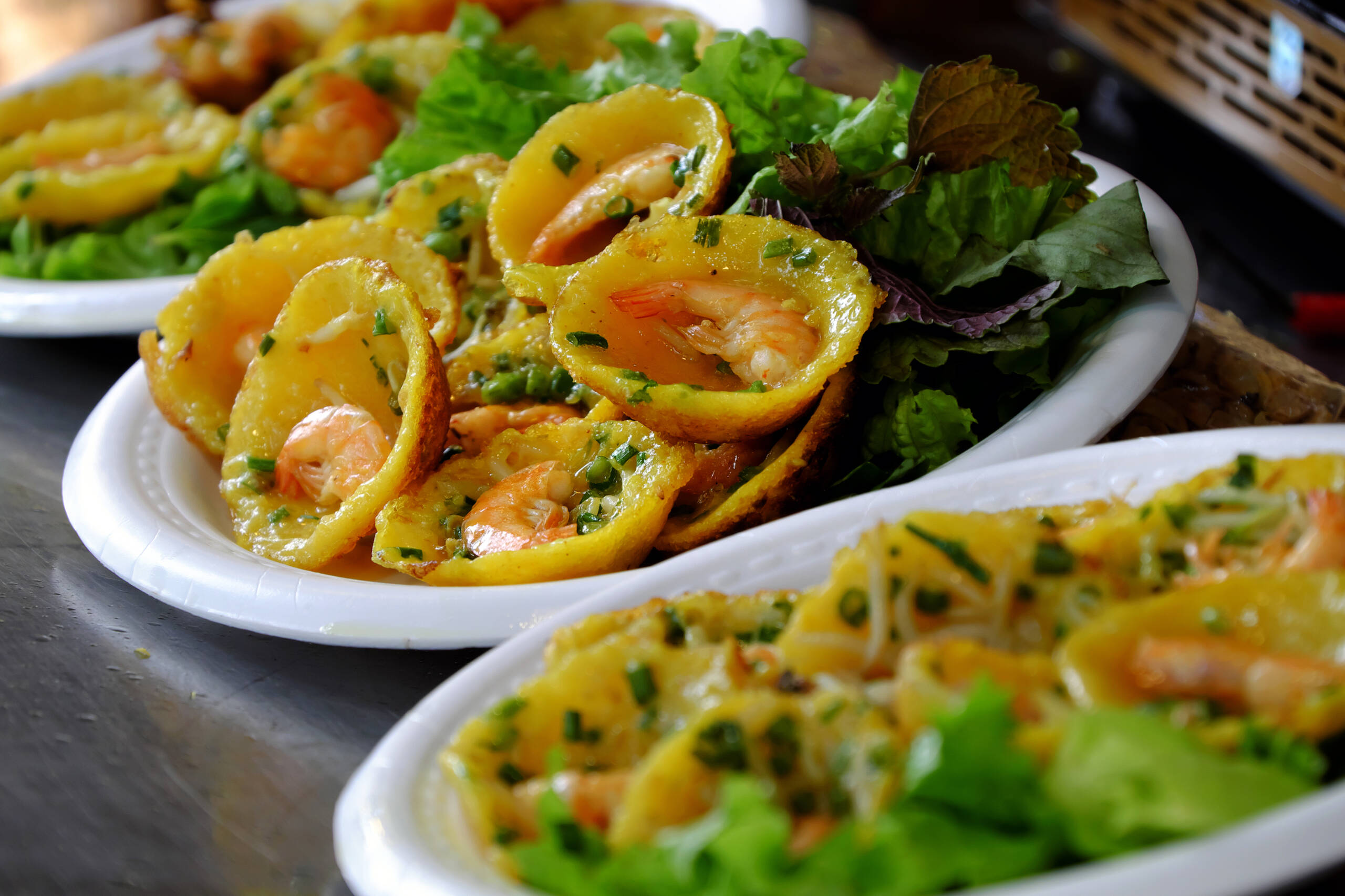 viaje por vietnam 10 dias - Vietnamese street food, yellow and delicious pancakes on plate at cuisine fair at Ho Chi Minh city