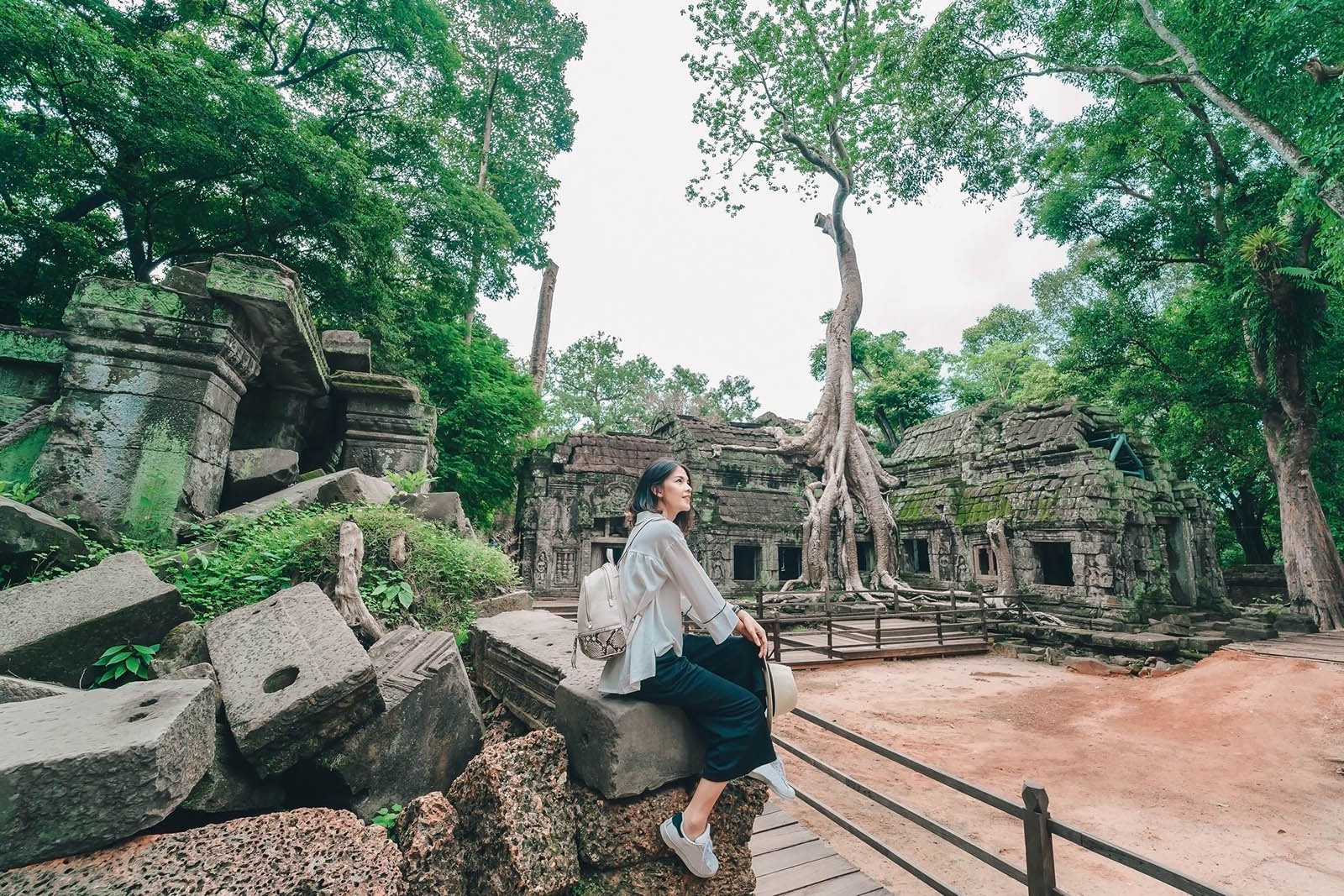 vietnam y camboya en 10 días Young female tourist wearing a hat with backpack is posing at Ta Prohm Temple